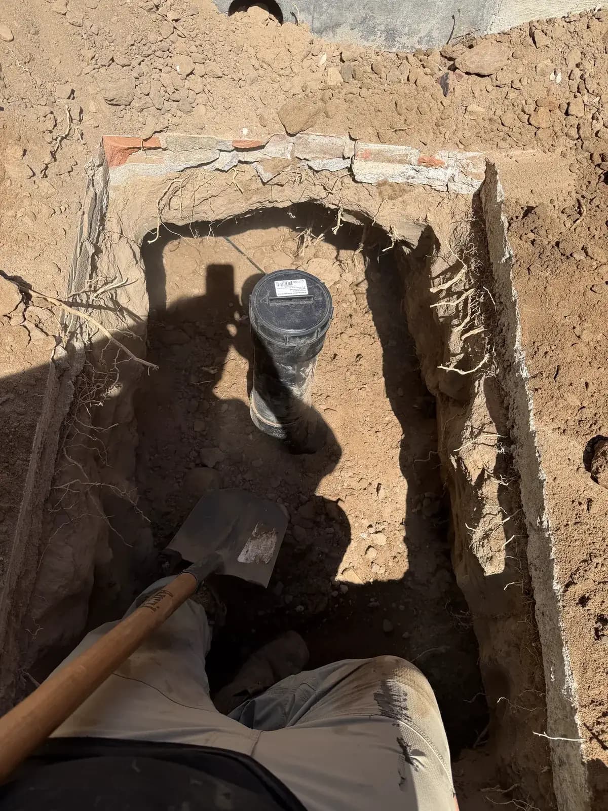 An open trench with a new sewer lateral and a cleanout riser set in it